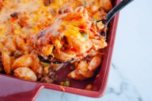 Hamburger Casserole in red baking dish with black spoon