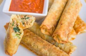 Italian Egg Rolls on a white plate with side of marinara sauce