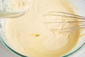 Melted shortening being poured into batter with whisk