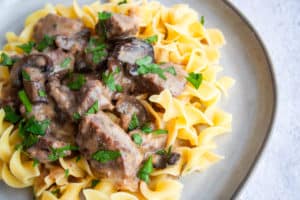 Beef stroganoff on egg noodles served on gray plate