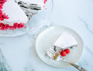 Plate of chocolate raspberry icebox cake with silver fork next to cake plate