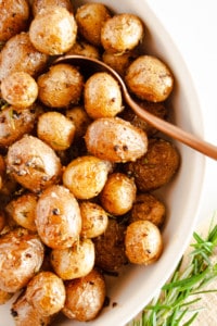 Rosemary Roasted Potatoes in a white serving dish with fresh rosemary