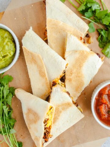 Mexican Breakfast Sheet Pan Quesadillas on wooden tray with guacamole, salsa and cilantro