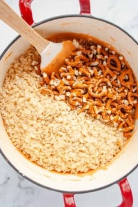 Rice krispy cereal and crushed pretzels in pot with marshmallow mixture