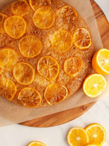 Lemon upside-down cake on wooden tray surrounded by lemon slices
