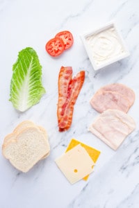 Ingredients for Classic Club Sandwich spread out on marble countertop