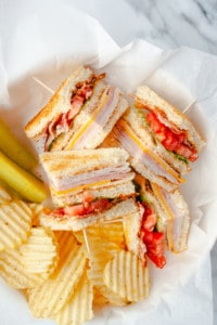 Quartered Classic Club Sandwich with potato chips and pickles