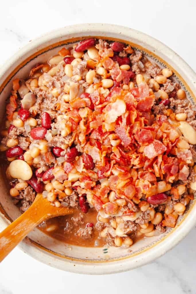 Mixture of beans, hamburger, onion and bacon in a mixing bowl