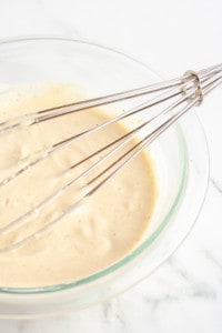 Homemade Caesar dressing in a glass bowl with a metal whisk