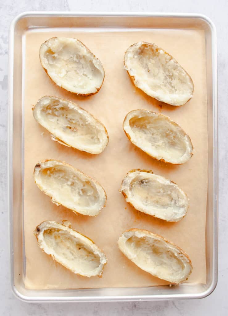 Baked potatoes halved and scooped out on baking sheet