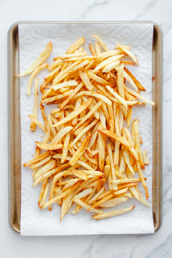 French fries after second fry on a paper towel lined sheet pan