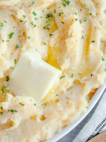 Mashed Rutabaga and Potato in a white serving dish with pat of butter on top