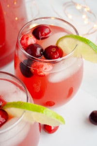 Two glasses of Holiday Punch garnished with cranberries and lime