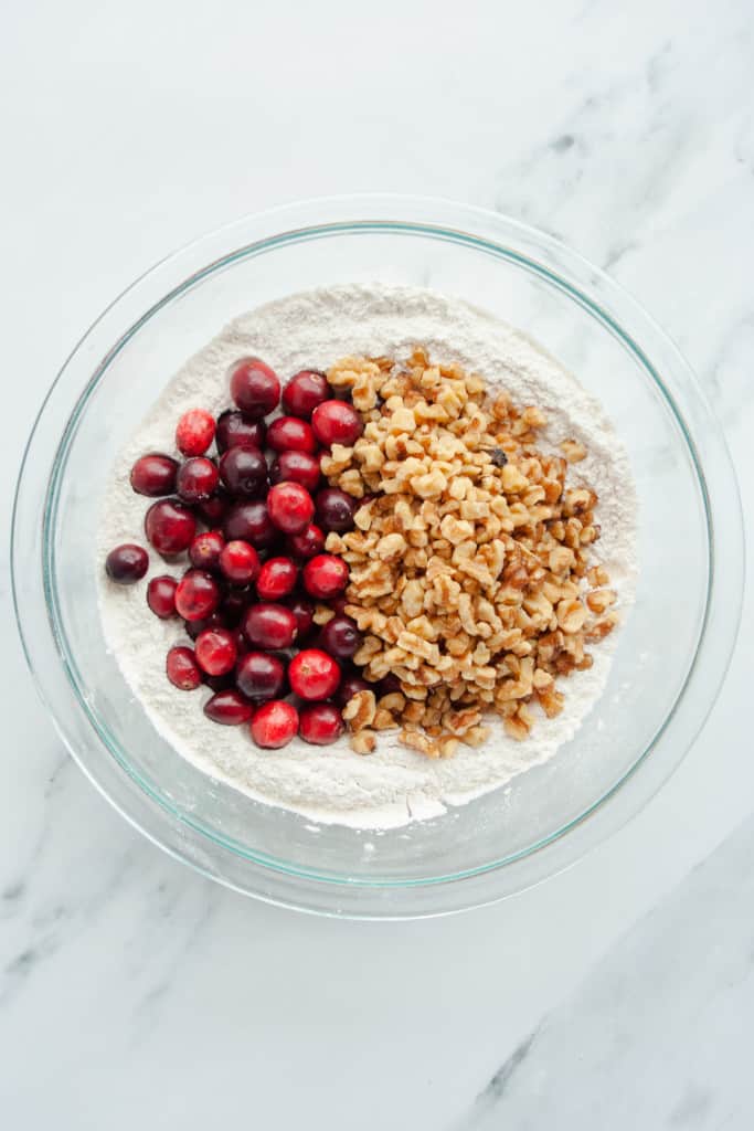 Cranberries and walnuts in a mixing bowl with dry ingredients