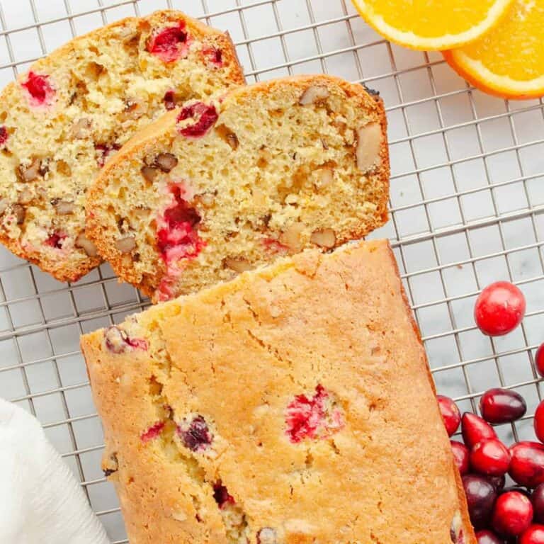 Loaf of Cranberry Walnut Bread on a wire rack with 2 slices cut
