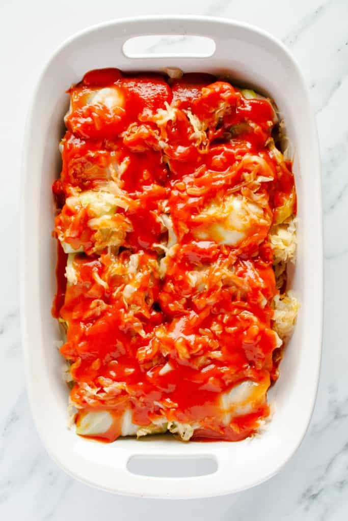 Baking Dish of Stuffed Cabbage Rolls topped with tomato sauce and sauerkraut