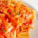 Two cabbage rolls on a plate with sauerkraut and tomato sauce