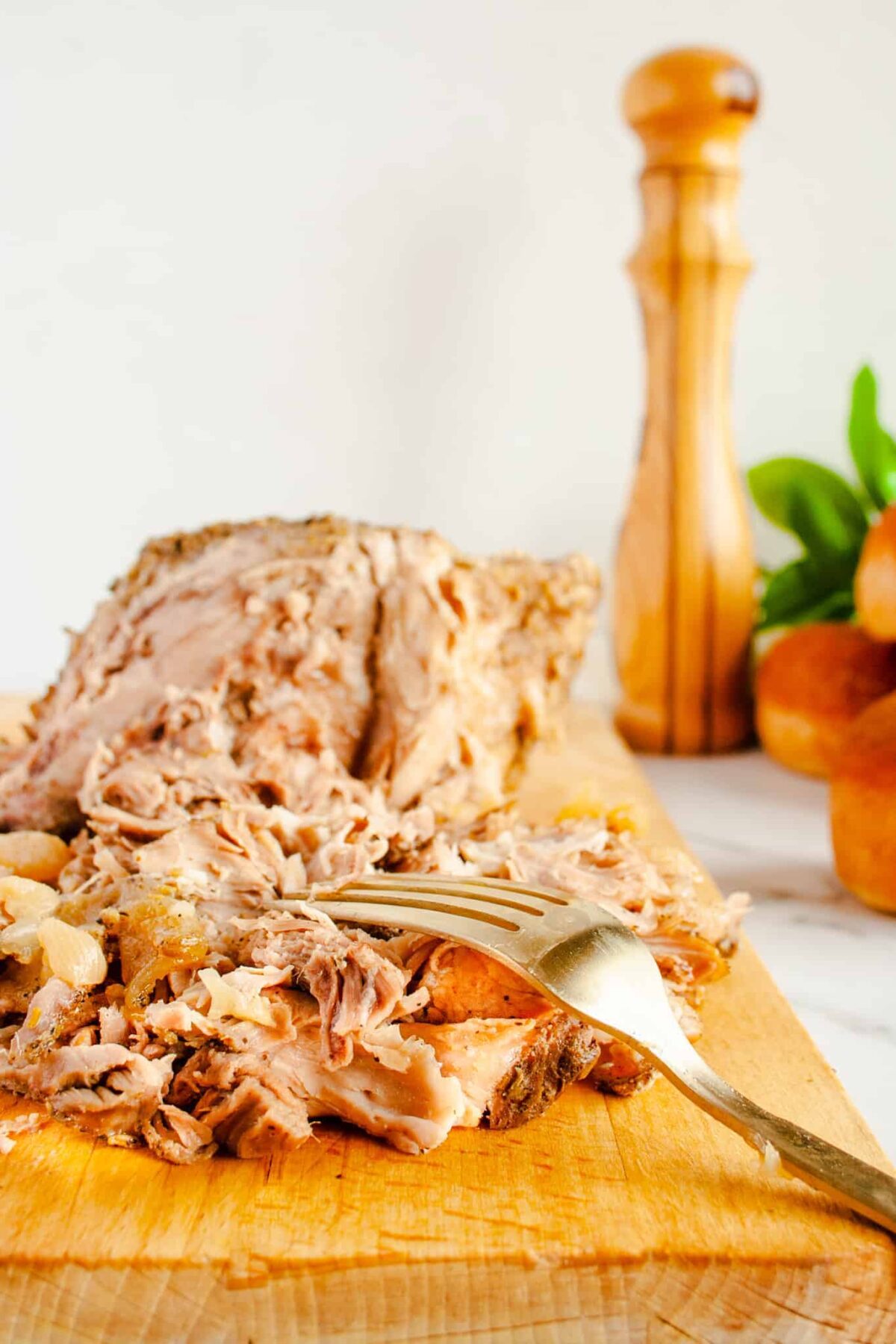 roast being shredded on wooden cutting board