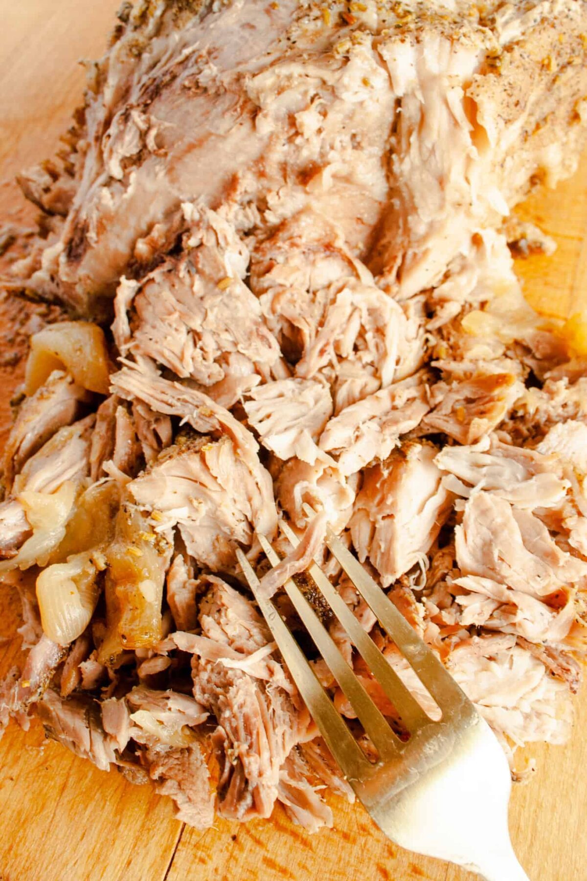 Shredded pork on wooden cutting pork with a fork