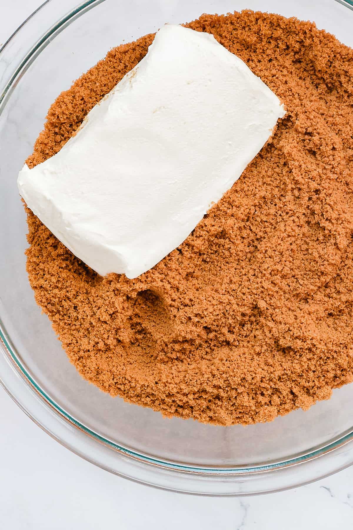 Block of cream cheese in a bowl of cookie crumbs