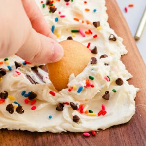 Hand dipping a vanilla wafer into frosting