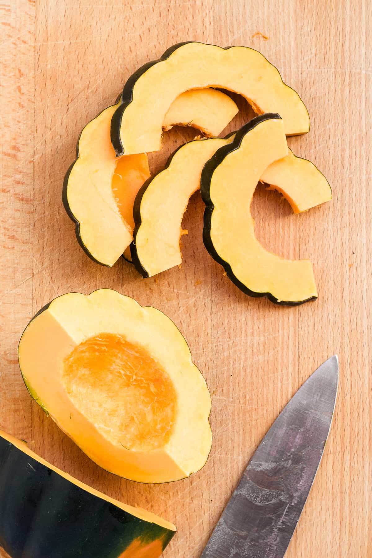 Squash cut into slices with large knife on cutting board