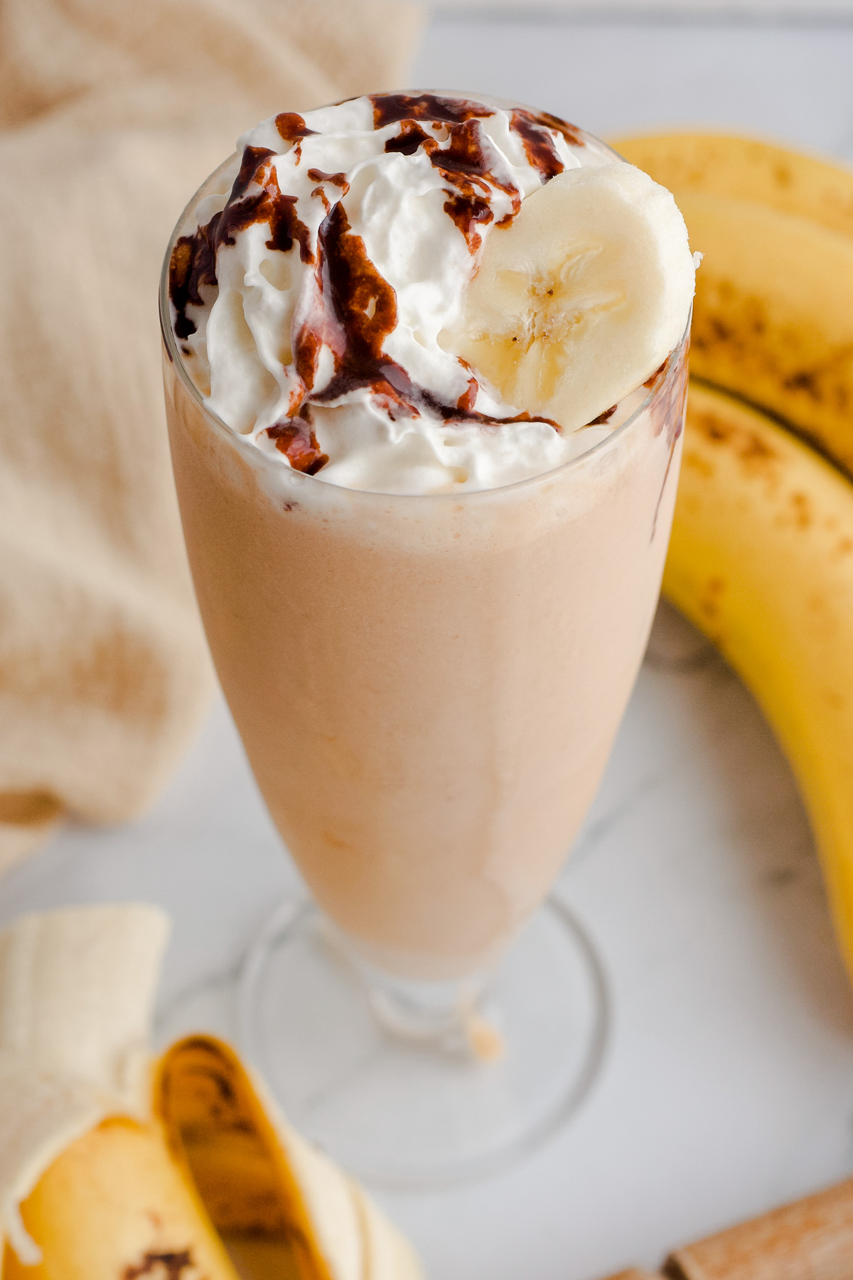 Monkey milkshake in a tall glass with whipped cream and chocolate syrup on top