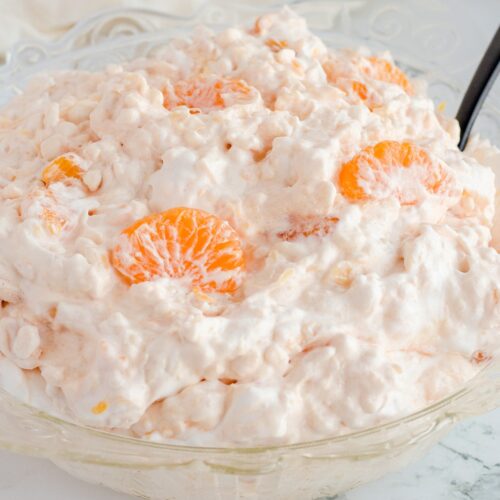 Jello salad in glass bowl with extra orange slices on top