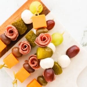 Meat and cheese skewers on a wood and marble cutting board