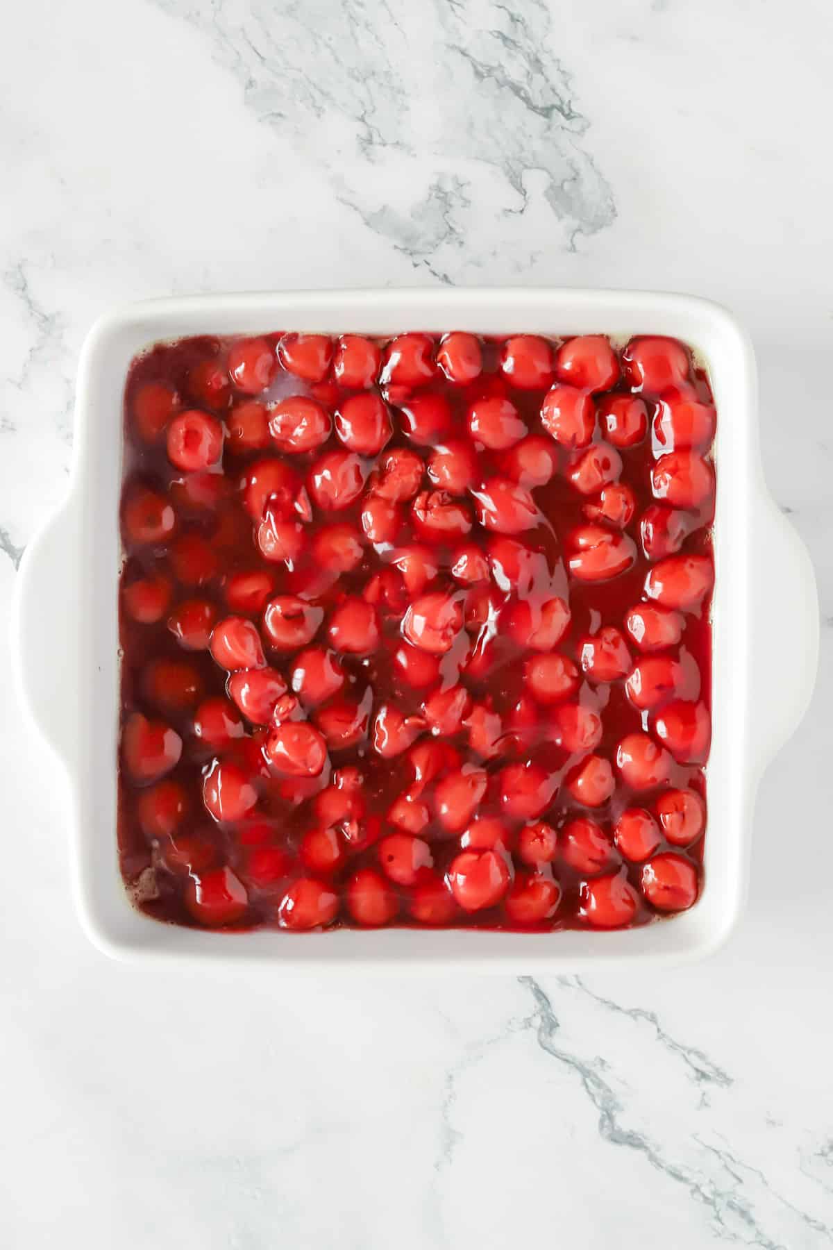 Canned pie filling spread in bottom of white 8x8 baking dish