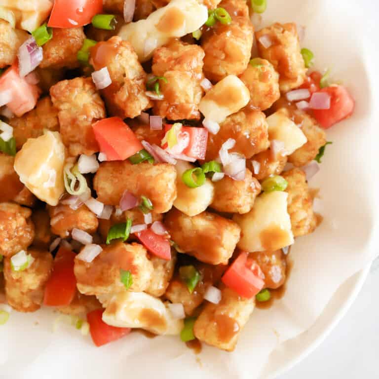Overhead view of poutine on a parchment lined white oval platter