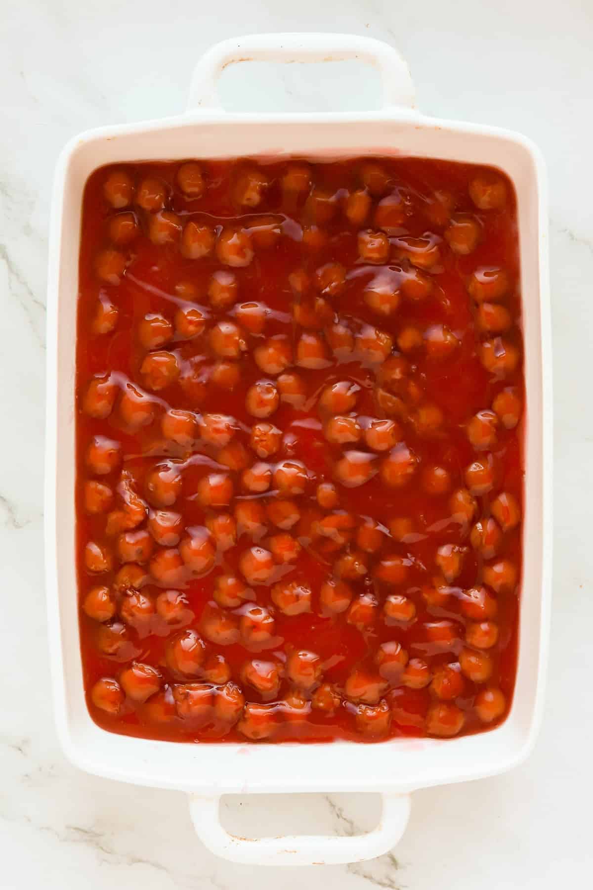 Canned pie filling spread in bottom of white 9x13 baking dish