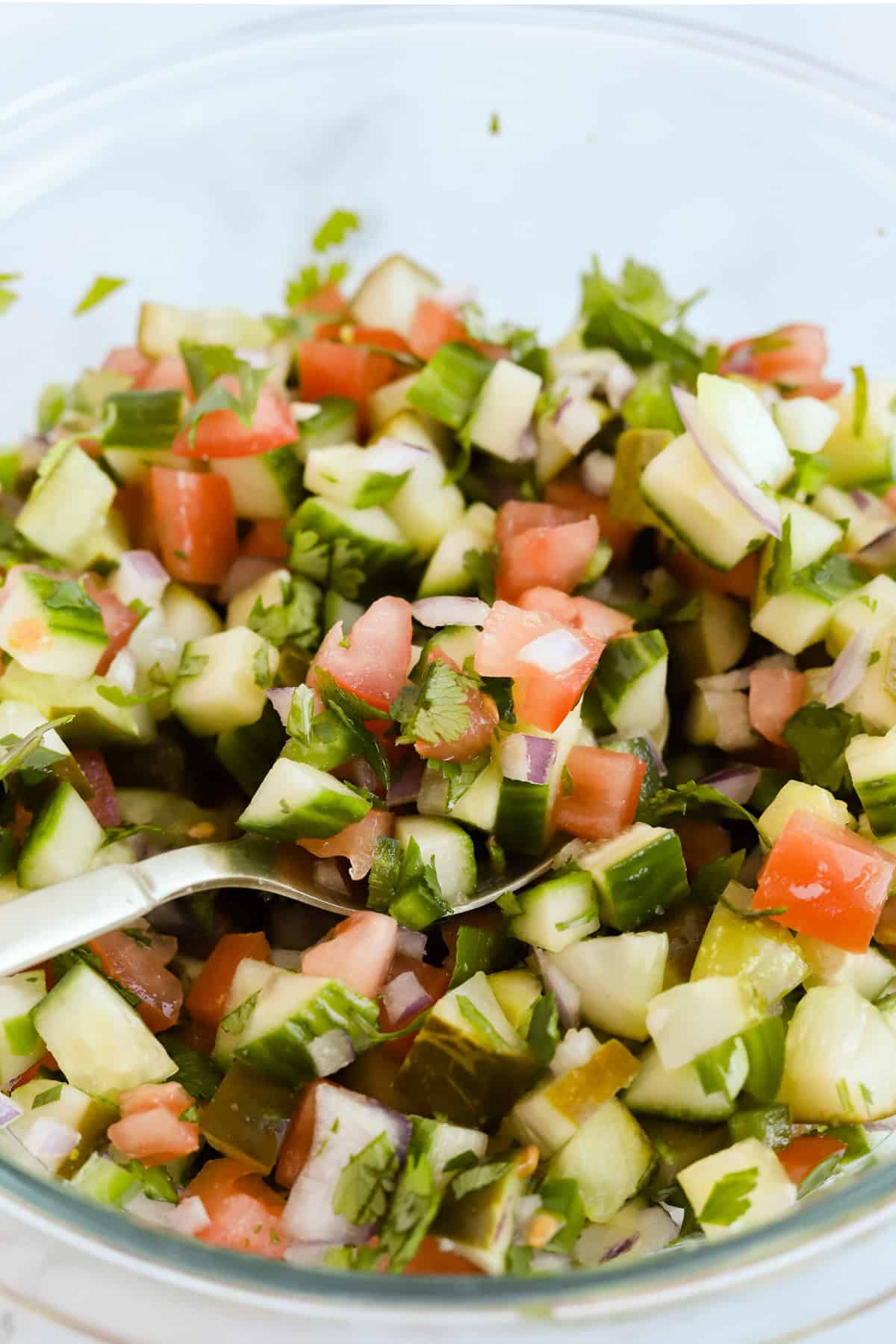 Mixed pickle de Gallo in a glass bowl mixed with a gold spoon