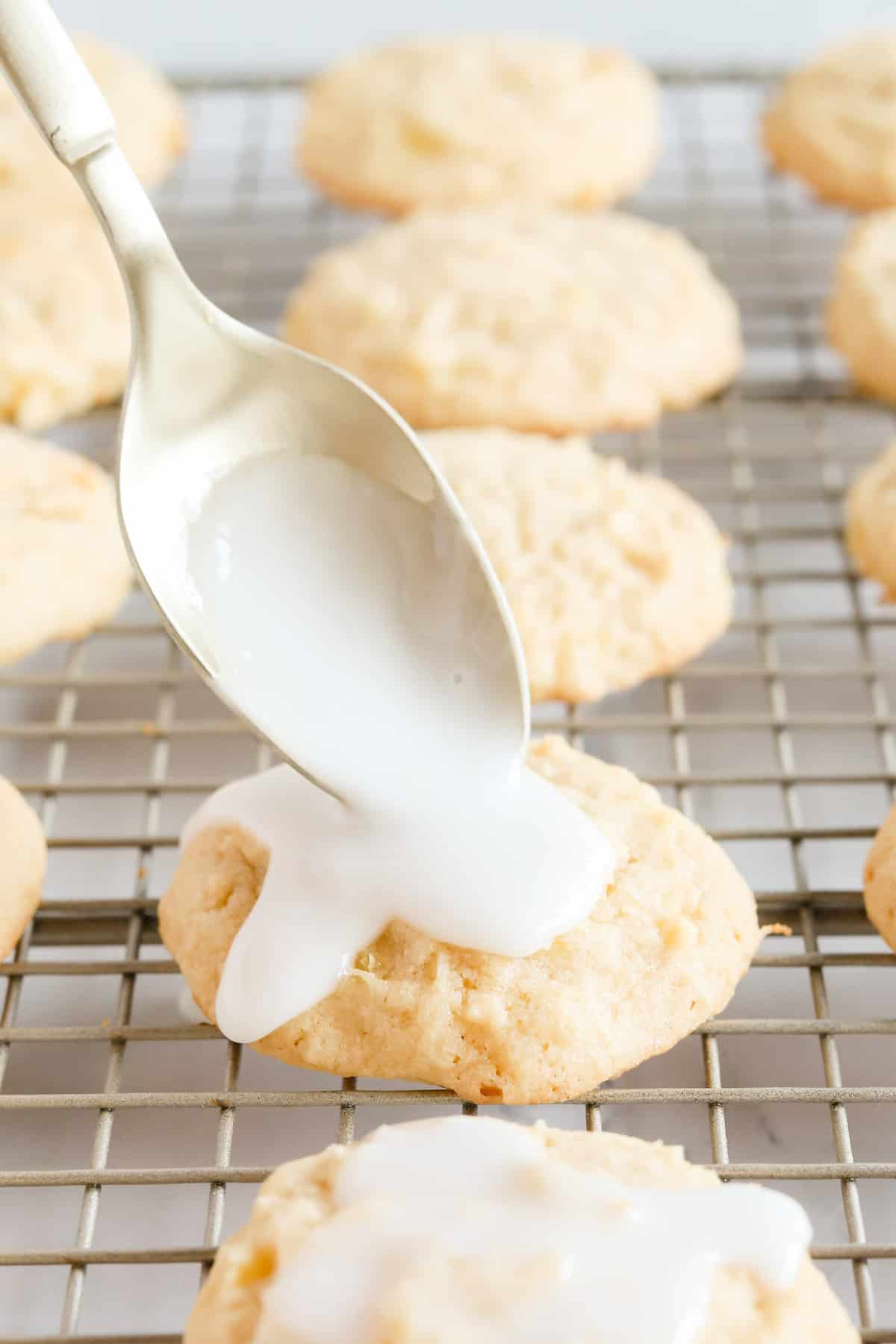 Gold spoon pouring pineapple glaze over the top of a cookie.