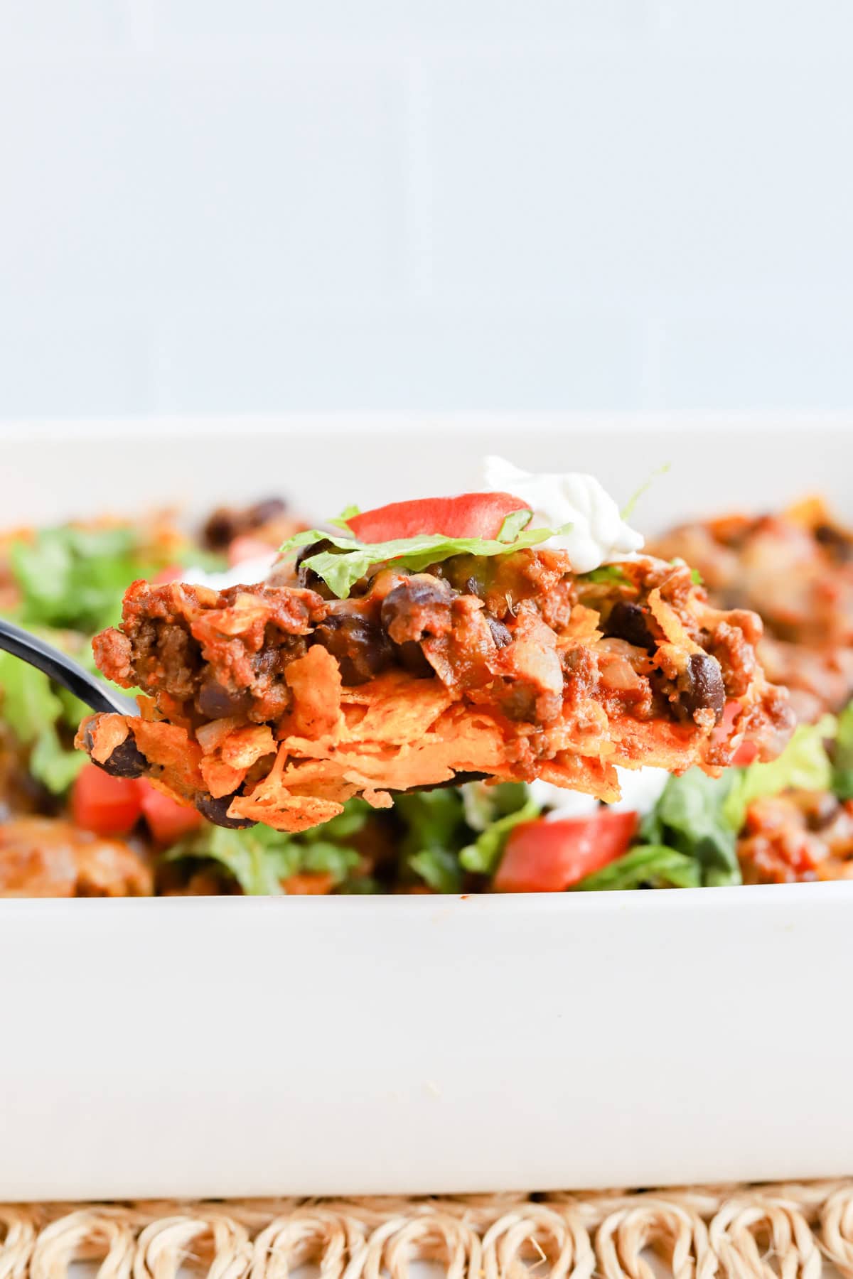 Black spoon scooping a spoonful of casserole out of baking dish.