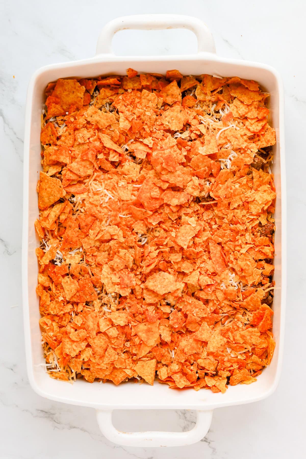 Second layer of crushed nacho cheese tortilla chips on casserole.
