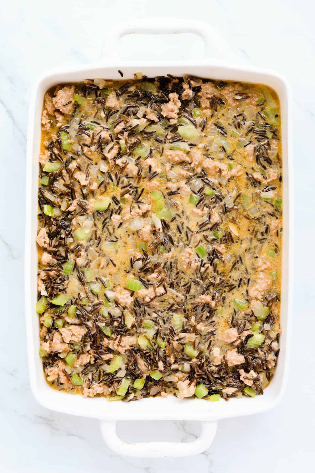 Uncooked casserole in a white baking dish.