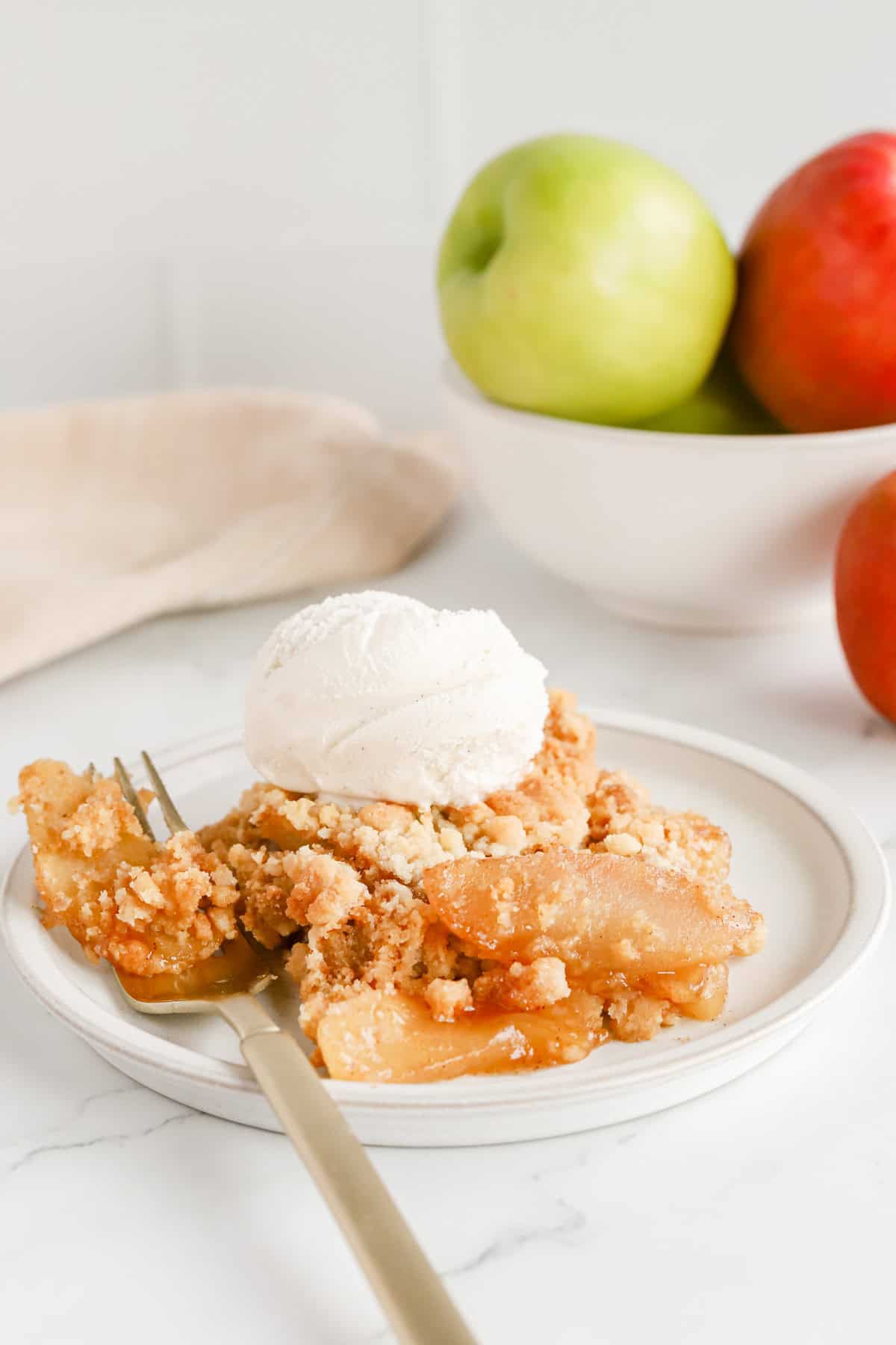 Plated apple cobbler with a scoop of vanilla ice cream on top.