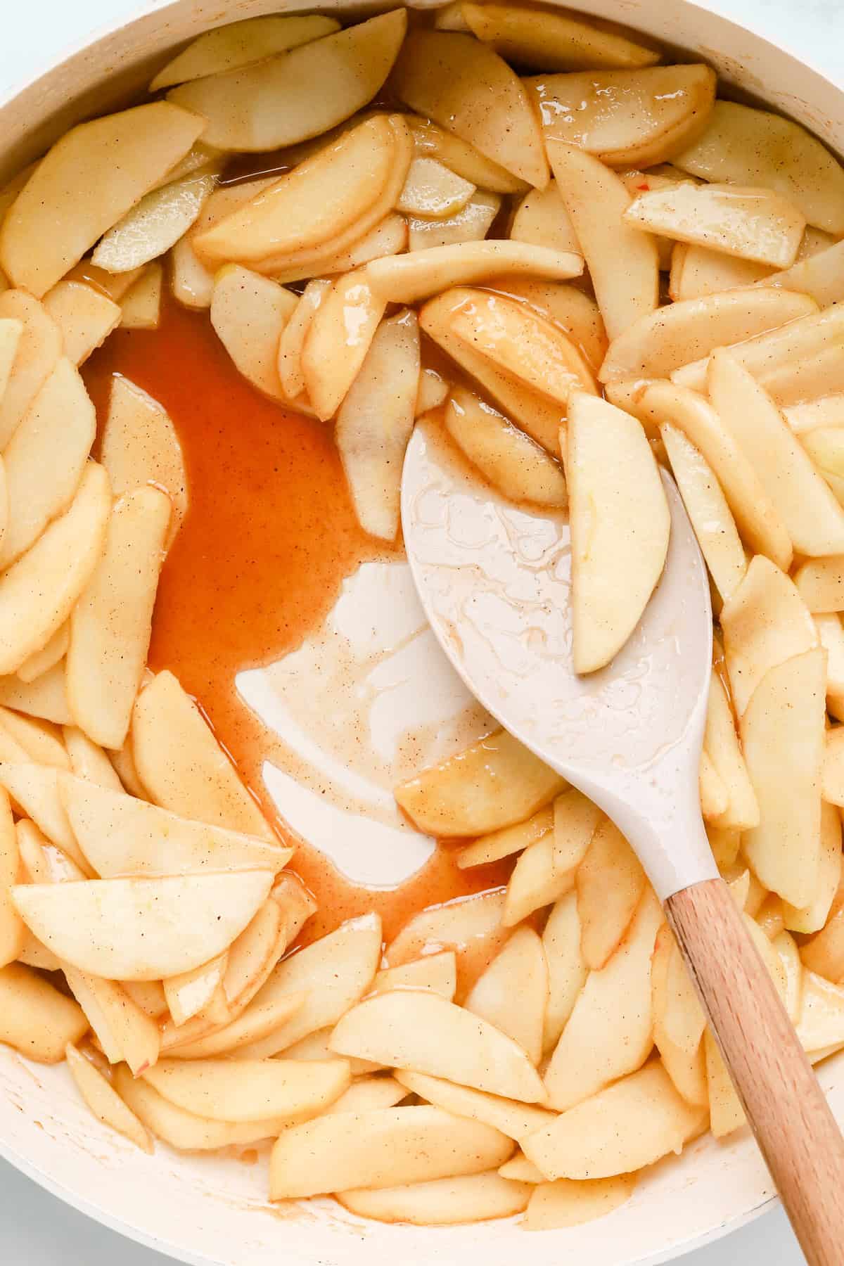 Fresh sliced apples cooking in caramel sauce, perfect for apple pie filling or desserts.