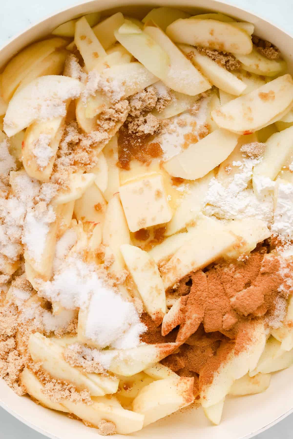 Sliced apples with filling ingredients in a skillet.