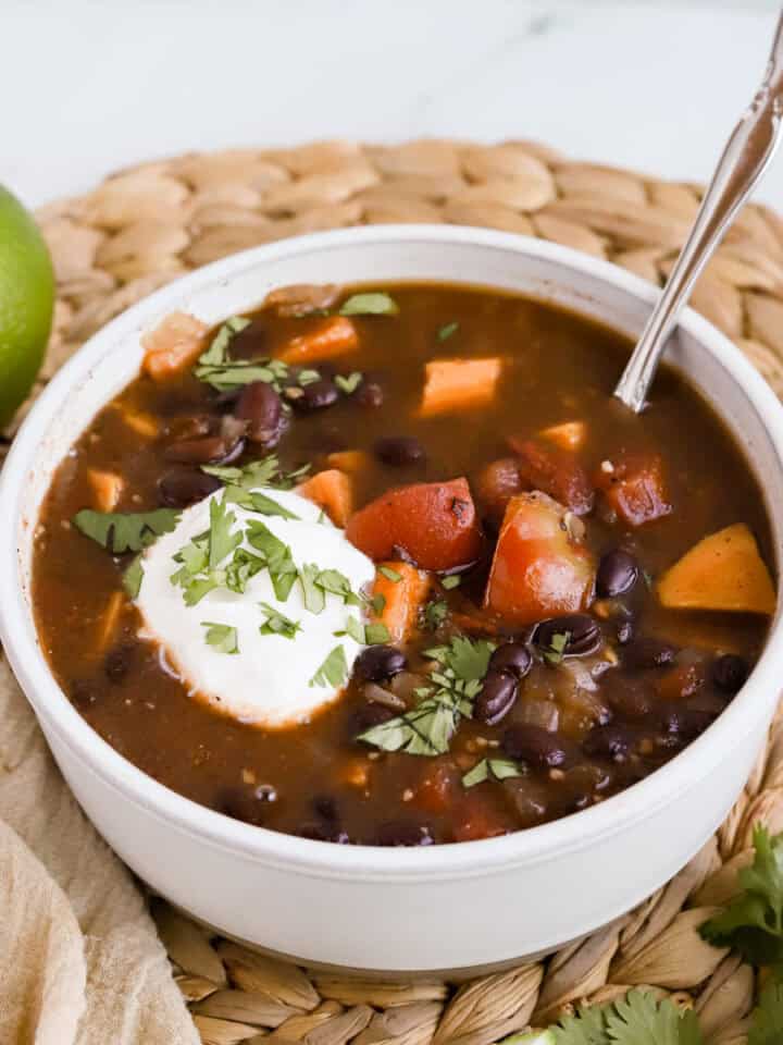 Square photo of bowl of soup garnished with sour cream and chopped cilantro.