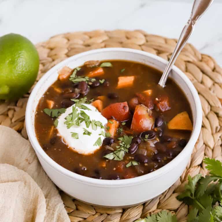 Square photo of bowl of soup garnished with sour cream and chopped cilantro.