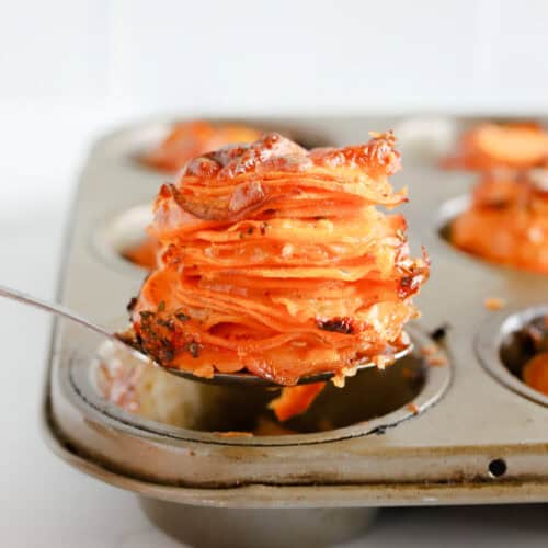 Square photo of a spoon lifting a potato stack out of the muffin tin.