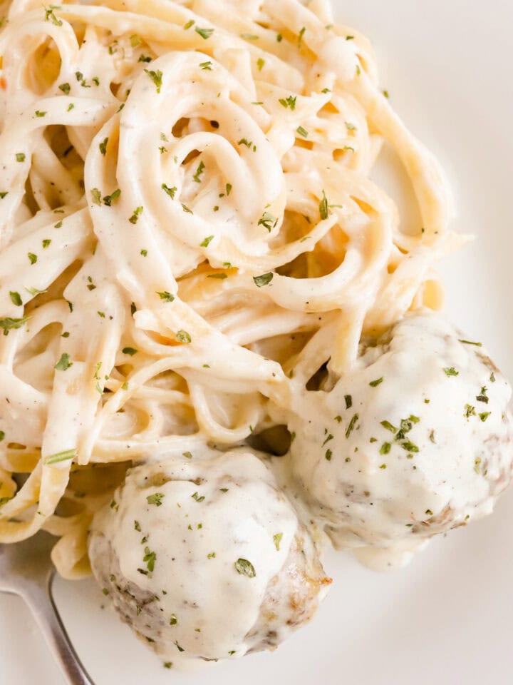 Square photo of fettuccine alfredo with meatballs.