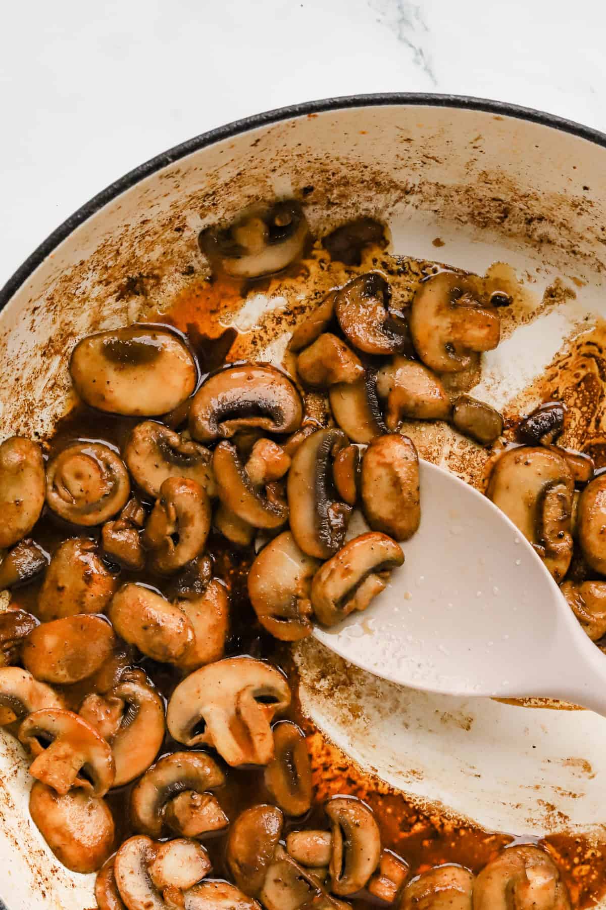 Golden brown white mushrooms sautéed in skillet.
