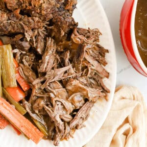Pot roast made with onion soup mix on a platter with carrots and celery.