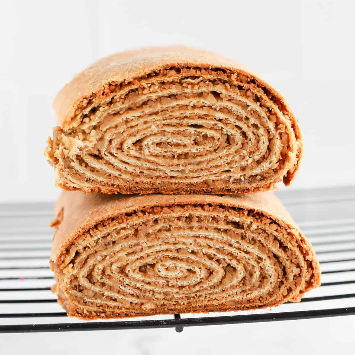 Potica loaves stacked on top of each other on wire rack revealing spiral center.