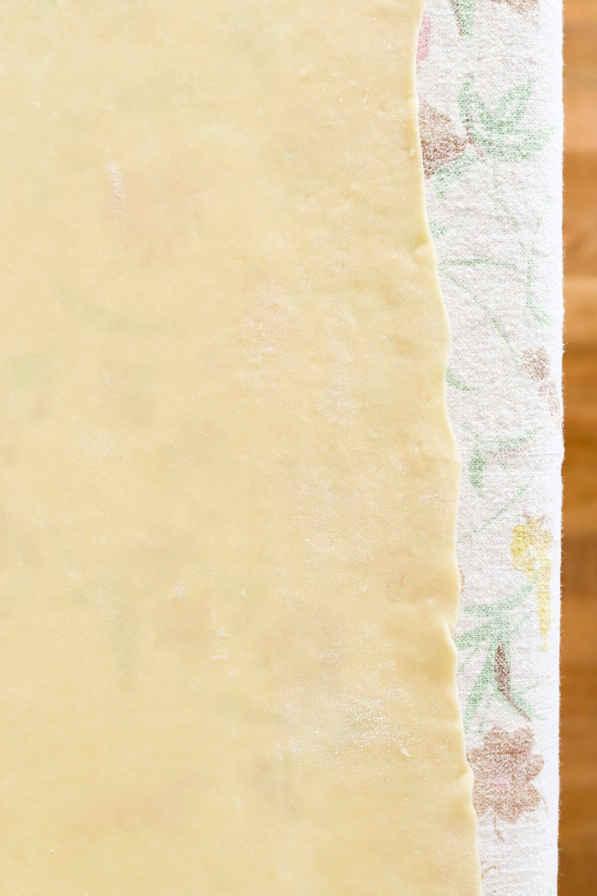 Yeast enriched dough rolled out thin on cotton tablecloth so you can see the flowers through the dough.