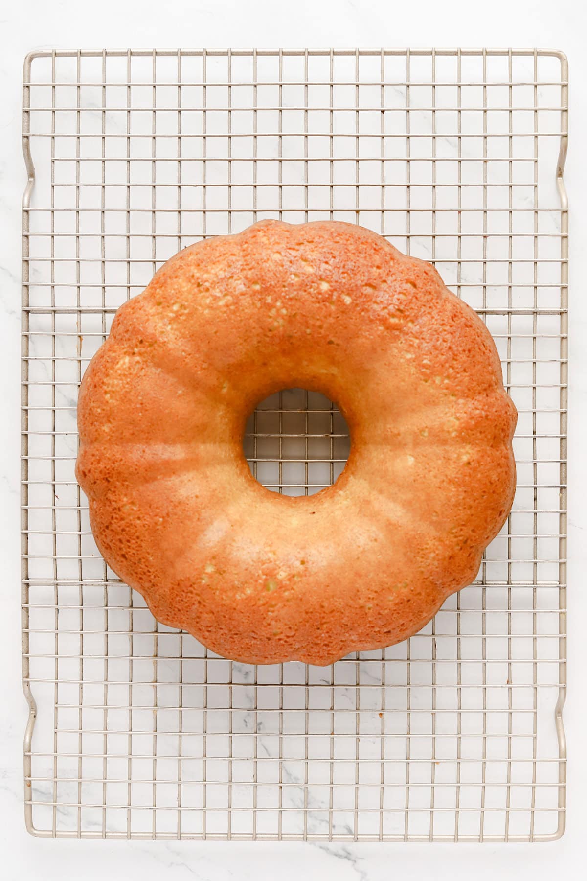 Baked pistachio bundt cake inverted onto a wire cooling rack.
