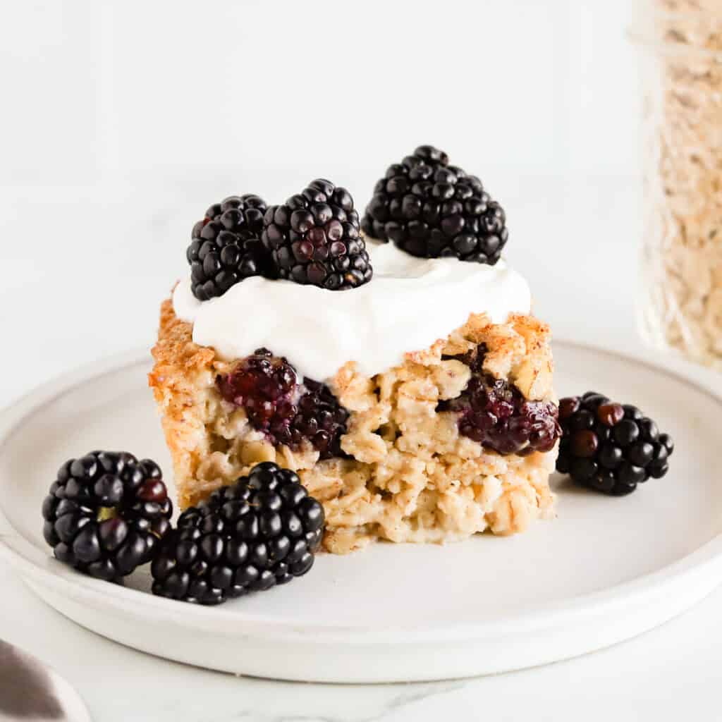 Square of baked oatmeal topped with vanilla yogurt and fresh blackberries.
